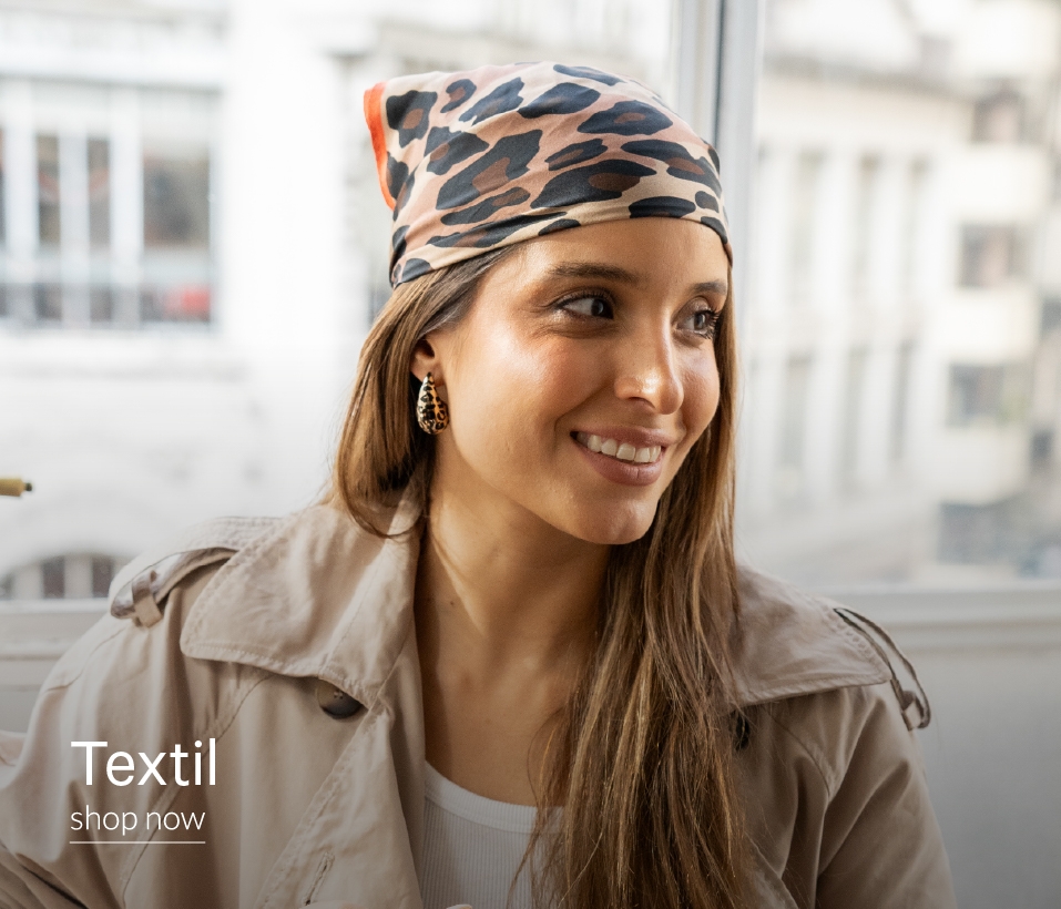 Mujer sonriendo con kimono y aros y collar con forma de corazon. Con inscripción "Textil. Shop Now"